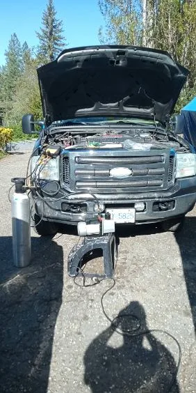Ford F-250 with hood up and full A/C service equipment connected — post-repair vacuum and charge performed on-site