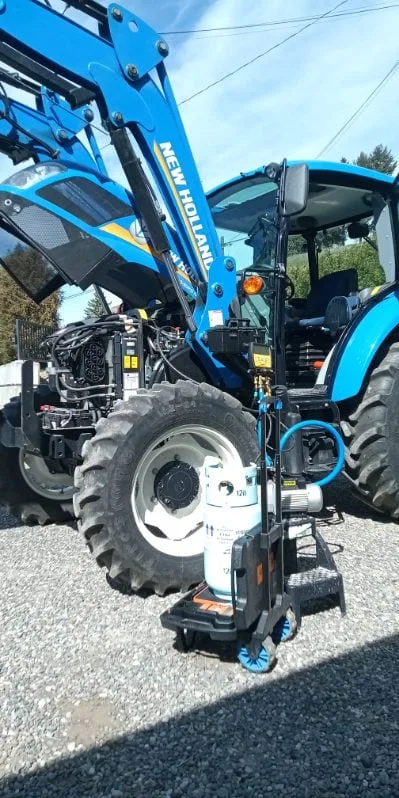 Mobile A/C recharge on a New Holland tractor at an Okanagan farm with vacuum pump and refrigerant cylinder staged